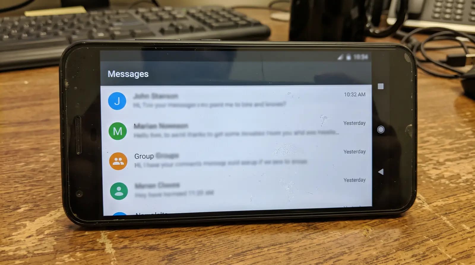 Phone on a desk showing a list of conversations